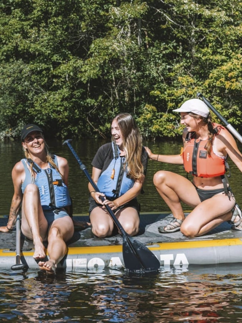 Groupe d'amies en planche à pagaie familiale l'été